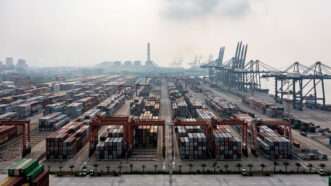 A shipping yard filled with shipping containers near a body of water | Photo: Jinli Guo/iStock